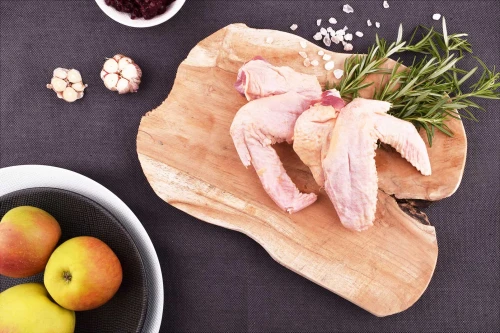 Surowe skrzydełka z kaczki EKO 220g na drewnianej desce z przyprawami