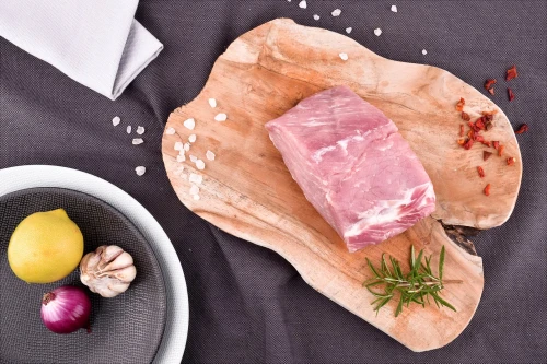 Surowy schab wieprzowy EKO bez kości 500g na drewnianej desce z przyprawami, cytryną i czosnkiem
