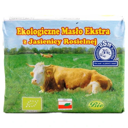 Kostka ekologicznego masła na papierze pergaminowym, widoczna kremowa konsystencja i naturalny kolor
