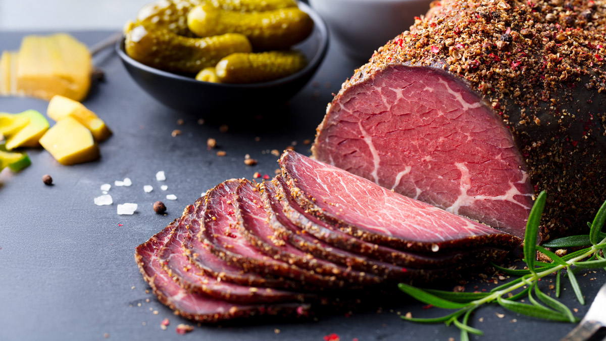 Plastry pastrami wołowego na drewnianej desce, z widoczną strukturą mięsa